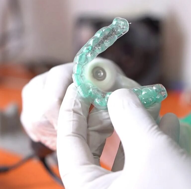 Dental technician trimming a finished clear aligner for quality control